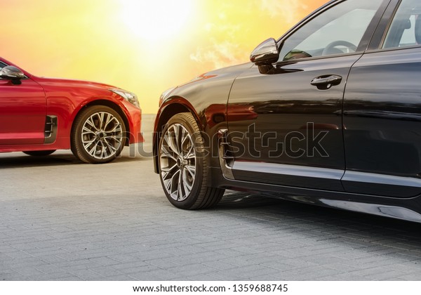 Red and black car under a bright sunny sky in\
the afternoon