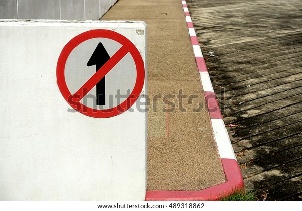 red and black don't go straight sign on white painted
wall beside to gravel floor ramp and concrete ramp.                
              