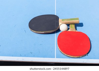 Red and black Table Tennis Paddles and ball on the blue table tennis table with net. Ping Pong concept with copy space - Powered by Shutterstock