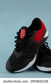 Red And Black Tennis Shoes For Running, With A Blue Background And Space For Text