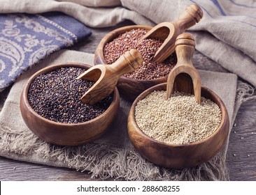 Red, black and white quinoa seeds on a wooden background