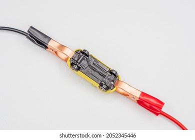 Red and black wire automotive clips or battery clamps on a yellow toy car on a white background. The concept of a quick start of the battery, starting the automobile engine in winter.