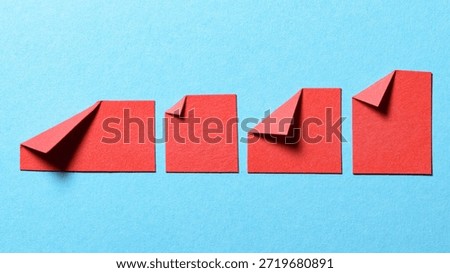 Red blank paper message notes or sheets with folded edge dog-ear earmark and copy space for text on blue background, top view flat lay conceptual desk backdrop