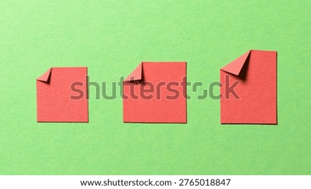 Red blank paper message notes or sheets with folded edge dog-ear earmark and copy space for text on green background, top view flat lay conceptual desk backdrop