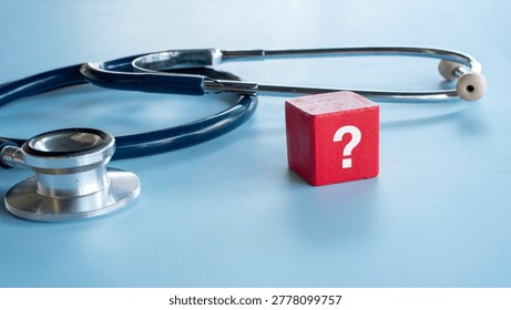 A red block with a white question mark standing next to a medical stethoscope on a blue background symbolizing medical uncertainty