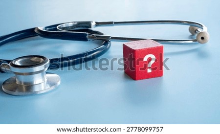 A red block with a white question mark standing next to a medical stethoscope on a blue background symbolizing medical uncertainty