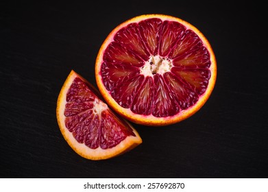 Red Blood Sicilian Orange Wedge And Half On Black Stone Background