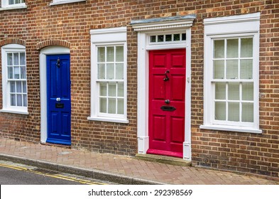 Red And Blue Front Doors And White Windows On A Terraced House In UK. Traditional British Doors.