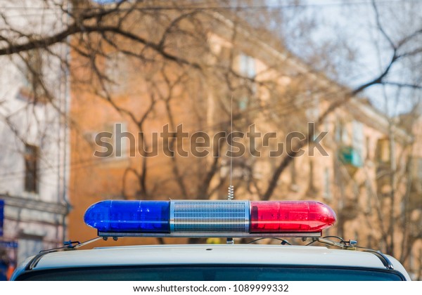 Red and blue\
light flasher of a police car. Siren on police car flashing. Blured\
street at the background