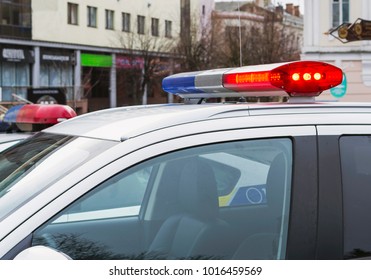 Red And Blue Lights Of Police Car In Day Time On Street Background. Patrolling The City, Crime Scene.Selective Focus.