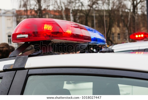 Red and blue lights of\
police cars in day time. Patrolling the city, crime scene.Selective\
focus.