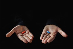 Red And Blue Pills On Hand Isolated On Black Background