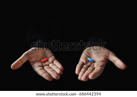 Red and blue pills on hand isolated on black background