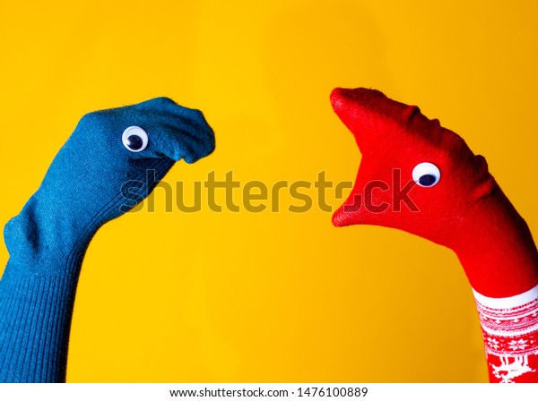 Red and blue sock puppets argue on the\
colorful yellow background