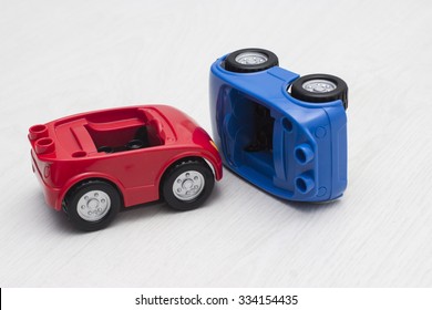 Red And Blue Toy Cars On The White Wooden Background As In A Car Crash