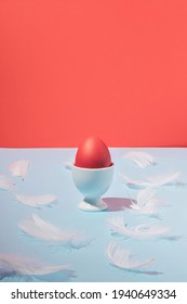 Red and blue vintage Easter composition with Easter egg and white feathers. Minimal, trendy concept.