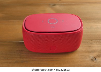 Red Bluetooth Speaker On Brown Wooden Table.