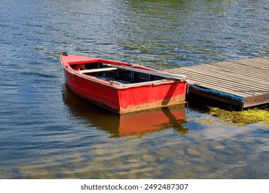 Red boat with oars at the pier.