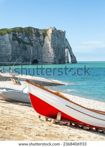A red boat standing on the seashore with elephant like sea cliff in the background in Étretat