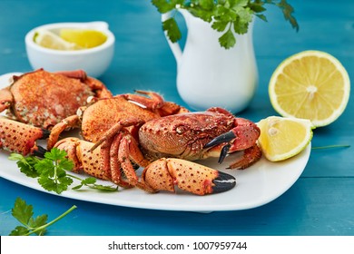 Red boiled crabs with a lemon and parsley on blue wooden background
