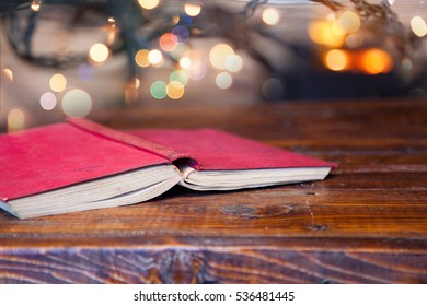 Red Book On Wooden Table - Fireplace And Christmas Tree In The Background - Cozy Home Concept