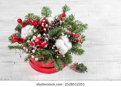 A red box with white flowers and pine cones inside. The box is placed on a white surface - Powered by Shutterstock