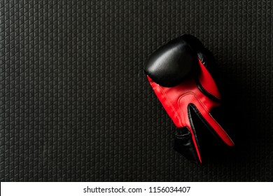 Red Boxing Glove On Black Rubber Floor In Boxing Gym.