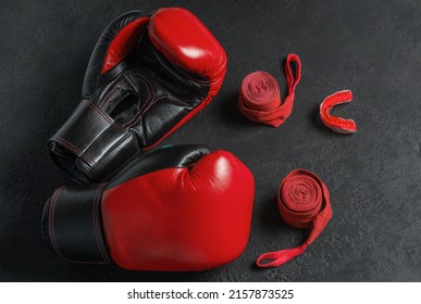 Red boxing gloves, cap and bandage on a black background.