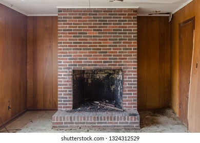 Red Brick Fireplace Set Against Wood Panel Walls In An Abandoned House In The Deep South