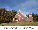 Red brick, Jearolds Town United Methodist Church, sits on a backroad of Tennessee.  White steeple is topped by a white cross.