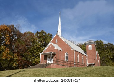 Red brick, Jearolds Town United Methodist Church, sits on a backroad of Tennessee.  White steeple is topped by a white cross. - Powered by Shutterstock