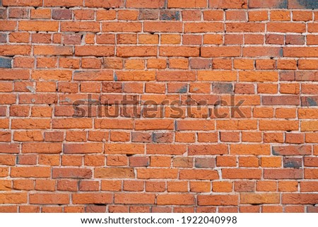 Red brick masonry wall, uneven, broken and black burnt bricks, bright red brick background