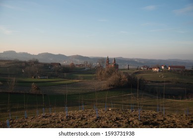 Red Brick Serb Orthodox Christian Church On Warm Winter Sunset In Surrounded With Grass Fields, Old Houses And Sheep In The Village Of Tutnjevac, Bosnia