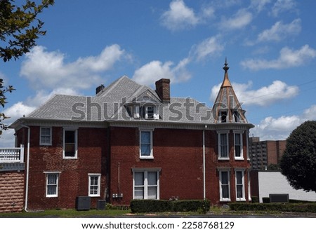 Red brick, Victorian Home, has turret with copper top and finial.  