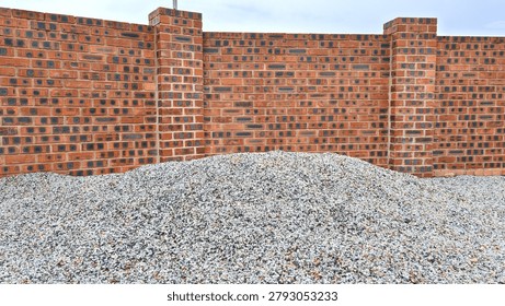 Red brick wall with dark patterns behind a mound of crushed gravel