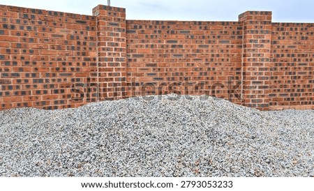 Red brick wall with dark patterns behind a mound of crushed gravel