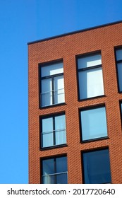 Red brick wall of a modern building against bright blue, clear sky on a sunny day. . High quality photo