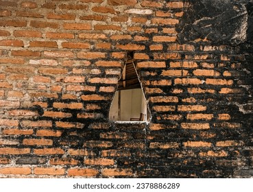 Red brick wall texture with a triangle hole. Kediri, East Java, Indonesia. January 09, 2023