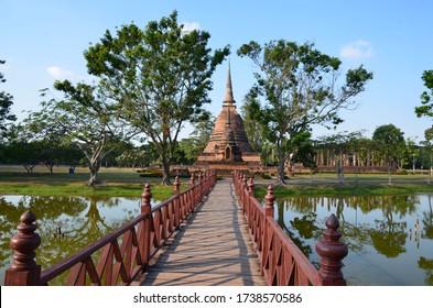 A Red Bridge Is Leading To Wat Sra Sri, A Beautiful Temple In The Historical Park Of Sukhothai