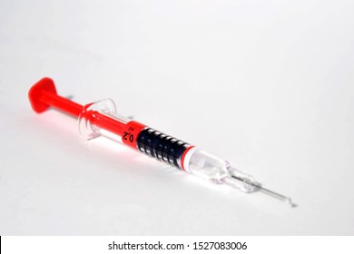 Red Bright Syringe Lying On White Background, Diabetes, Blood Thinning Or Vaccination Concept