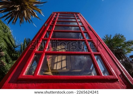 Red British vintage telephone box, looking up, a striking picture taken in wide view with contrast and shadows. A true example of a traditional British icon. Widely known in the UK.