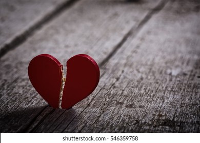 red broken heart on wooden background - dark and moody
