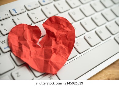Red broken heart paper on white keyboard computer background. Online internet romance scam or swindler in website application dating concept. Love is bait or victim.