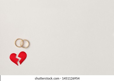 Red Broken Heart Split In Two Pieces With Pair Of Golden Wedding Rings, Top View, Flat Lay, Divorce And Breakup Concept, Copy Space