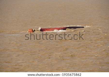 Red brown painted bottom of the capsized ship with rudder and propeller in the muddy dirty river approaching to the Shanghai, China.