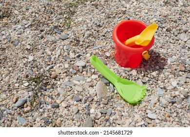 Red bucket, green rake and yellow beach shovel on the beach sand on a sunny summer day, Vera, Spain