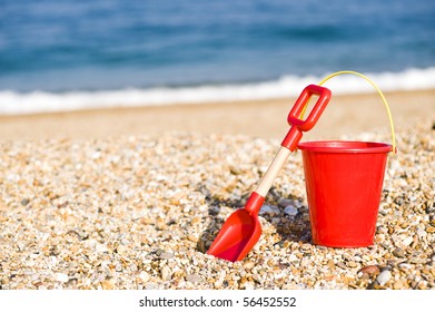 Red Bucket And Spade Lying On A Beach