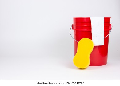 Red Bucket With Wash Cloth And Sponge On White Background. Spring Cleaning, Household Chores, Car Washing Concepts.