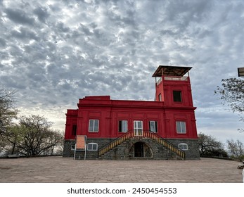 A red building with a sign on the front at Ralamandal, Indore, India. The building is surrounded by trees and has a large staircase leading up to it. - Powered by Shutterstock