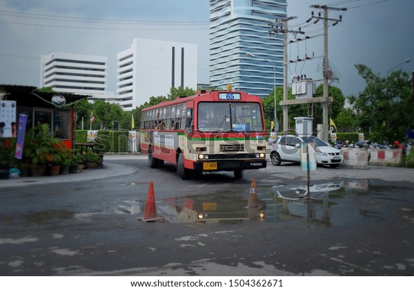 Red bus is turning at the corner\
after rain before stop and take passengers safety Bangkok public\
bus transportation in Thailand Asia August 14\
2019